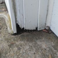 Mice were gaining access into a garage in Wilmington, MA. We sealed off the rotted entrance with some Metal and Mortar. (Before)